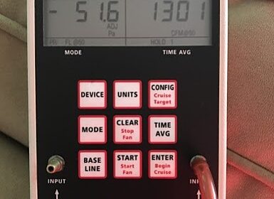 Numbers on the pressure and flow gauge device on a Blower Door.